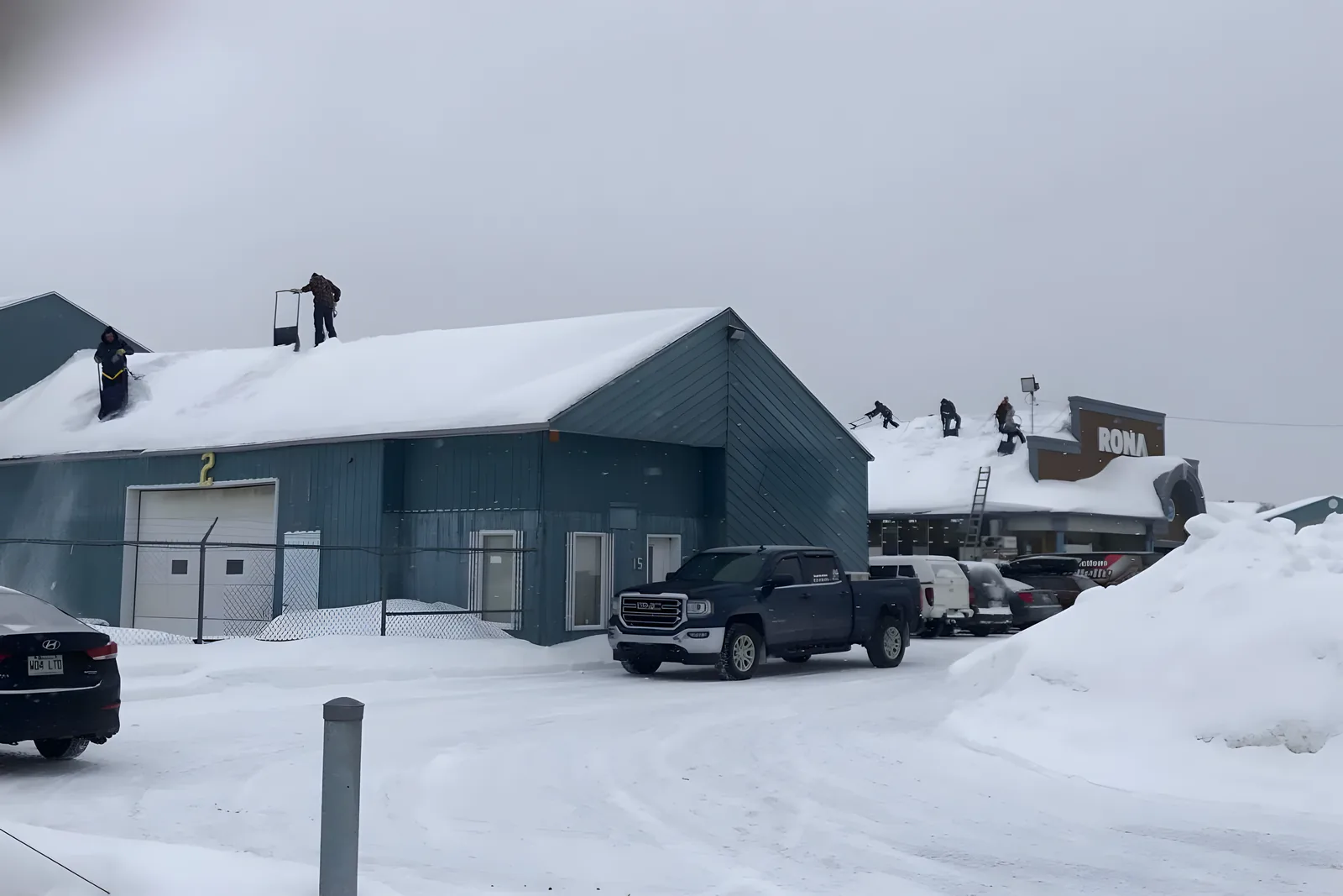 Plusieurs personnes déneigent des toitures commerciales pendant l’hiver